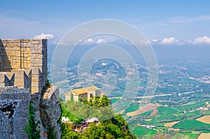 Aerial top panoramic view of Basilica Pieve, Palazzo Pubblico palace and landscape with valley, green hills, San Marino
