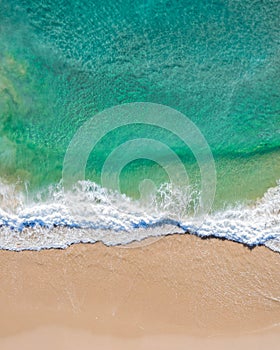 Aerial top shot of a beach with nice sand, blue turquoise water and tropical vibe