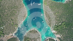 Aerial top view from above of white luxurious yachts embarked in bay with turquoise, crystal clear water in Croatia, France,