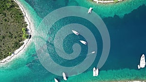 Aerial top view from above of white luxurious yachts embarked in bay with turquoise, crystal clear water in Croatia, France,