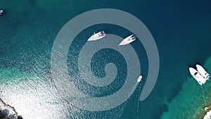 Aerial top view from above of white luxurious yachts embarked in bay with turquoise, crystal clear water in Mediterranean  country