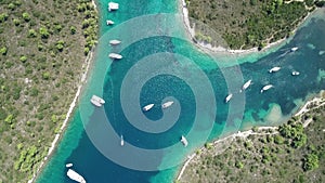Aerial top view from above of white luxurious yachts embarked in bay with turquoise, crystal clear water in Mediterranean  country