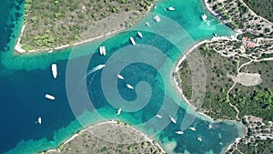 Aerial top view from above of white luxurious yachts embarked in bay with turquoise, crystal clear water in Mediterranean  country