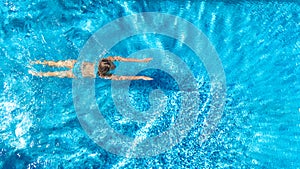 Aerial top view of active woman in swimming pool from above, girl swims in blue water, tropical vacation, holiday on resort