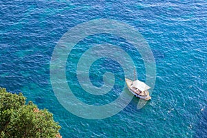 Aerial top view of alone white yacht or boat sailing on azure water, in blue sea, Amalfi coast, Italy