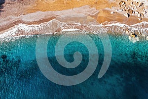 Aerial top view of azure sea waves and sandy beach coast in sunny summer day, drone photo