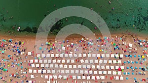 Aerial top view on the beach. Umbrellas, people, sand and sea waves