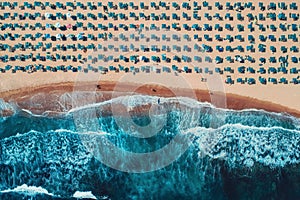 Aerial top view on the beach. Umbrellas, sand and sea waves