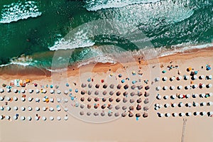 Aerial top view on the beach. Umbrellas, sand and sea waves