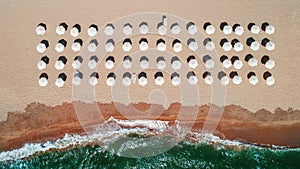 Aerial top view on the beach. Umbrellas, sand and sea waves