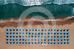 Aerial top view on the beach. Umbrellas, sand and sea waves