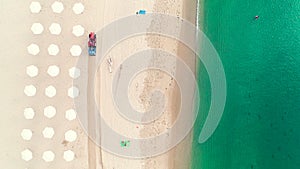 Aerial top view on the beach. Umbrellas, sand and sea waves. Summer holidays.