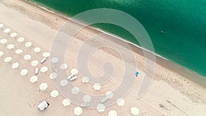 Aerial top view on the beach. Umbrellas, sand and sea waves. Summer holidays.