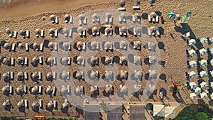 Aerial top view on the beach. Umbrellas, sand, sun chairs and sea waves