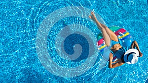 Aerial top view of beautiful girl in swimming pool from above, relax swim on inflatable ring donut and has fun in water