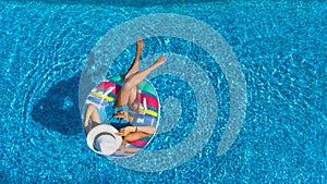 Aerial top view of beautiful girl in swimming pool from above, relax swim on inflatable ring donut and has fun in water