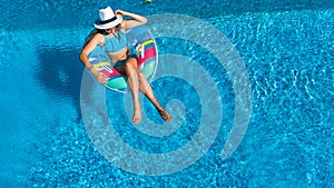 Aerial top view of beautiful girl in swimming pool from above, relax swim on inflatable ring donut and has fun in water