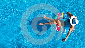 Aerial top view of beautiful girl in swimming pool from above, relax swim on inflatable ring donut in water on family