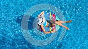 Aerial top view of beautiful girl in swimming pool from above, relax swim on inflatable ring donut in water on family