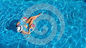Aerial top view of beautiful girl in swimming pool from above, relax swim on inflatable ring donut in water on family