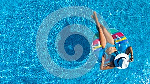 Aerial top view of beautiful girl in swimming pool from above, relax swim on inflatable ring donut in water on family