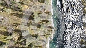 Aerial top view of a beautiful river with clear water. Clip. Cold blue and fast river and stony shore from one side and