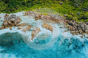 Aerial top view of beautiful tropical Anse Marron beach. Ocean waves hitting granite rocks along coastline, La Digue