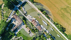 Aerial top view of boats and lock in Canal du Midi, road and bridge from above, France