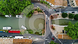 Aerial top view of boats and lock in Canal du Midi, road and bridge from above, France