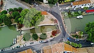 Aerial top view of boats and lock in Canal du Midi, road and bridge from above, in Southern France