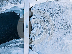 Aerial top view of bridge road above frozen river in snow winter Finland