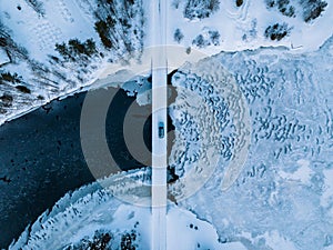 Aerial top view of bridge road above frozen river in snow winter Finland
