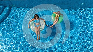 Aerial top view of children in swimming pool from above, happy kids swim on inflatable ring donuts in water on family