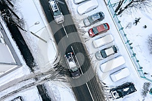 Aerial top view of city street after snowfall with parked cars and car traffic. aerial top view