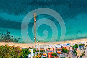 Aerial top view of colorful umbrellas on sandy beach, swim in blue sea summer sunny day. Tropical island sandy azure bay