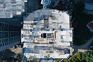Aerial top view of construction site of modern concrete buildings with industrial machinery equipment, cranes, workers