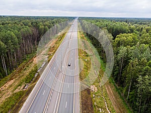 Aerial top view of a country road through a fir forest