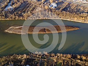 Aerial top view, countryside panorama of small island with dry grass in quiet river on sunny day. Drone photography