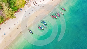 Aerial top view of crystal clear sea water and white beach with longtail boats from above, tropical island or Krabi province