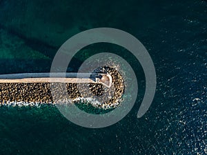 Aerial top view by drone of iconic Venetian lighthouse in the entrance of picturesque old port of Chania at sunset on Crete island