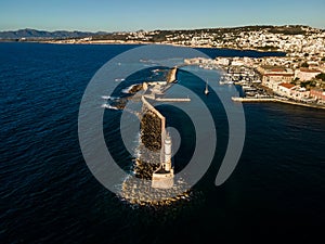 Aerial top view by drone of iconic Venetian lighthouse in the entrance of picturesque old port of Chania at sunset on Crete island