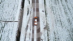 Aerial top view from drone of suv vehicle driving on snowy ice road exploring local landscapes in winter, birds eye view