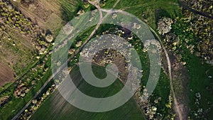 Aerial top view of early spring land, rural roads between agricultural lands and forest, high flying, drone footage.