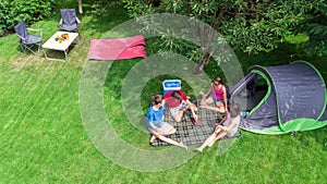 Aerial top view of family in campsite from above, parents and kids relax and have fun in park, tent and camping equipment