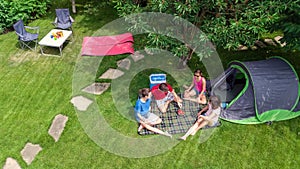 Aerial top view of family in campsite from above, parents and kids relax and have fun in park, tent and camping equipment