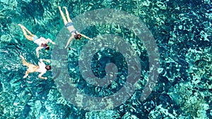 Aerial top view of family snorkeling from above, mother and kids snorkelers swimming in a clear tropical sea water, Thailand