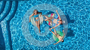 Aerial top view of family in swimming pool from above, happy mother and kids swim on inflatable ring donuts and have fun in water