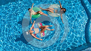 Aerial top view of family in swimming pool from above, happy mother and kids swim on inflatable ring donuts and have fun in water