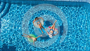 Aerial top view of family in swimming pool from above, happy mother and kids swim on inflatable ring donuts and have fun in water