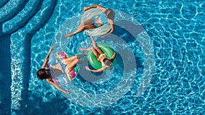 Aerial top view of family in swimming pool from above, mother and kids swim and have fun in water on family vacation
